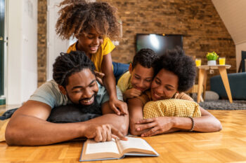 Beautiful family relaxing at home and reading a book together